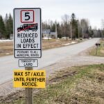 a white roadsign saying that 5 tonnes max standing by a melting snow roadway.